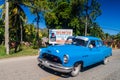 VINALES, CUBA - FEB 18, 2016: Vintage car and a propaganda poster near Vinales village, Cuba. It says: The dreams of all
