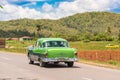 VINALES, CUBA - MAY 13, 2017: American green retro car rides along the road. Copy space for text.