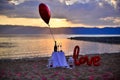 Vine glasses,balloon,  lamps and love script balloon on the beach at sunset. Love and romance theme Royalty Free Stock Photo