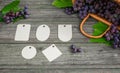Vine with grapes and leaves on vintage rustic wooden table. Set of differents paper tags template in center Royalty Free Stock Photo