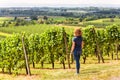 Vineyard rows overlooking grape fields, young woman looks at green vine plantation Royalty Free Stock Photo