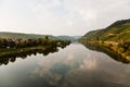 vineyards at the hills of the romantic river Mosel edge in summer with fresh grapes and reflection in the river