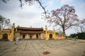 Vinh Phuc, Vietnam - Mar 22, 2017: Temple with blooming bombax ceiba tree and a female monk sweeping temple yard in Lap Thach dist