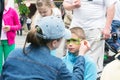 a woman paints the boy`s face with colors, during the celebration of Europe Day