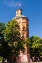 Historical building of water tower shine in sundawn, chestnut tree hide clock on the wall, Vinnytsia, Ukraine