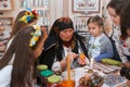 Old woman pysankar teaches little girls to write a floral folk ornament on Easter egg pysanka, Vinnytsia, Ukraine, 19.03.2018