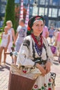 Portrait of a pretty young girl in Ukrainian traditional clothes, leaning on her bicycle, holding a smartphone, authentic look