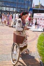 Pretty young girl in Ukrainian traditional clothes, leaning on her bicycle, checks the smartphone, true authentic ancient fashion