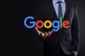 VINOGRADIV, UKRAINE - 30 DECEMBER 2020. Businessman in a suit on a dark background holds a Google logo inscription. Google is