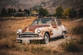 Vintage abandoned rusty car in a field under the sunlight in the countryside