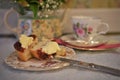 Vintage afternoon tea with floral crockery and scone with cream and jam