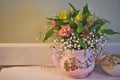 Table with old fashioned teapot and sugar bowl filled with fresh flowers