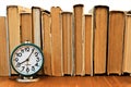 Vintage alarm clock on the background of a stack of old books