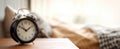 The vintage alarm clock on a bedside table in a cozy bedroom setting..AI generated image Royalty Free Stock Photo