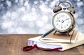 A vintage alarm clock and books on wooden table with glowing gl Royalty Free Stock Photo