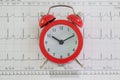 Vintage alarm clock lies on cardiogram paper in clinic