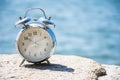 Vintage alarm clock on natural stone with the sea blurred background Royalty Free Stock Photo