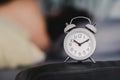 A vintage alarm clock is placed on the head of the bed. Conceptual media to wake up calls. Holiday break I do not work on time.