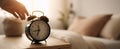 The vintage alarm clock resting on a bedside table in a warm bedroom setting..AI generated image Royalty Free Stock Photo