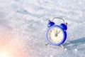 Vintage alarm clock on the snow at sunset. The concept of Christmas and New Year. Royalty Free Stock Photo