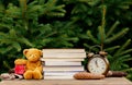 Vintage alarm clock, teddy bear and books on wooden table with spruce branches on background Royalty Free Stock Photo
