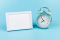 Photo frame and blue alarm clock on blue background with copy space Royalty Free Stock Photo