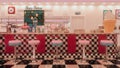 3D rendering of vintage American ice cream parlour with black and white checked floor and pink stools at the bar. Royalty Free Stock Photo