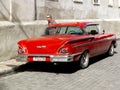 Vintage american red car in a paved cuban street. Royalty Free Stock Photo