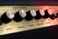 Vintage amplifier five knobs diagonal closeup, magenta