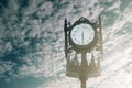 Vintage analogue clock against sunset with beautiful clouds.