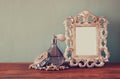 Vintage antigue perfume bottles with old picture frame, on wooden table. retro filtered image.