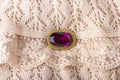 Vintage antique brooch with a large semi-precious purple stone on delicate ivory-colored lace cloth. Oldfashioned decoration from