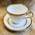 Vintage Antique Fine Bone China with Gold Trim Teacup and Saucer on Burlap Background Royalty Free Stock Photo