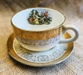 Vintage Antique Victorian Couple and Gold Trim Teacup and Saucer on Burlap Background