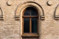 Vintage arched window in the wall of yellow brick. Black glass in a maroon dark red wooden frame. The concept of antique Royalty Free Stock Photo