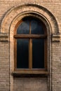 Vintage arched window in the wall of yellow brick. Black glass in a maroon dark red wooden frame. The concept of antique Royalty Free Stock Photo
