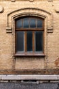 Vintage arched window in the wall of yellow brick. Black glass in a maroon dark red wooden frame. The concept of antique Royalty Free Stock Photo