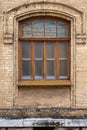 Vintage arched window in the wall of yellow brick. Black glass in a maroon dark red wooden frame. The concept of antique Royalty Free Stock Photo