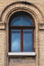 Vintage arched window in the wall of yellow brick. Black glass in a maroon dark red wooden frame. The concept of antique Royalty Free Stock Photo