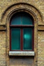 Vintage arched window in the wall of yellow brick. Green - the colors of sea wave glass in a maroon dark red wooden Royalty Free Stock Photo