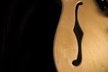 Vintage archtop guitar in natural maple close-up from above on black background, F-hole detail Royalty Free Stock Photo