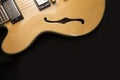 Vintage archtop guitar in natural maple close-up from above on black background, F-hole detail Royalty Free Stock Photo