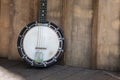 Vintage Banjo-mandolin, close up of the body, in sunlight on a wooden deck porch.