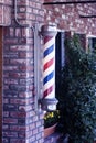 A vintage barber pole on wall ourside barber shop.