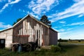 Vintage barn with barrels and tires in front Royalty Free Stock Photo