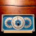 Vintage barometer with thermometer and hygrometer, shown against a weathered wood background.