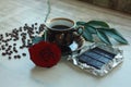 Vintage beautiful cup of hot coffee, bright red rose, green leaves, scattered coffee beans and dark chocolate bar on a wooden tabl Royalty Free Stock Photo