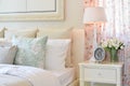 Vintage bedroom interior with decorative table lamp, alarm clock and flower on white table