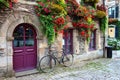 Vintage bicycle in front of the old rustic house, covered with flowers. Beautiful city landscape with an old bike near the stone Royalty Free Stock Photo