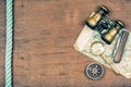 Vintage binoculars, compass, old map, magnifying glass, pocket knife, rope on wooden background Royalty Free Stock Photo